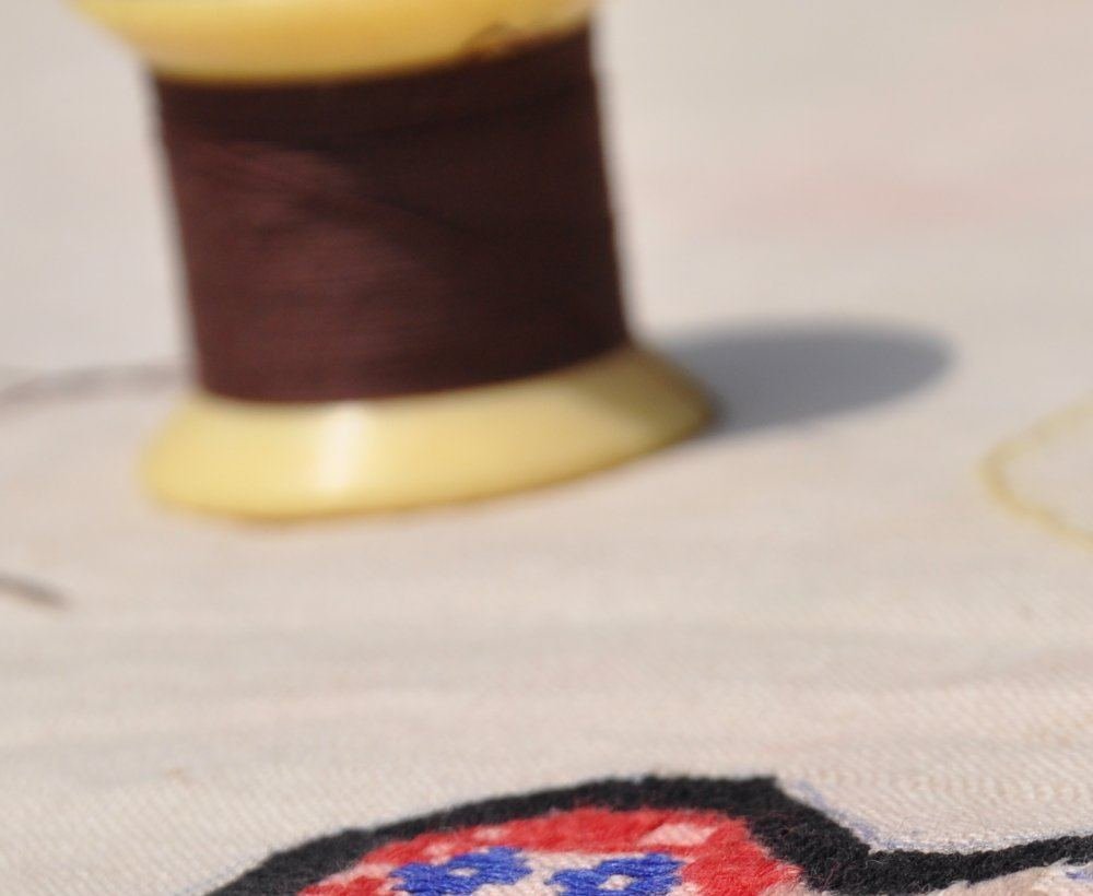 A spool of thread beside a hand-worked motif